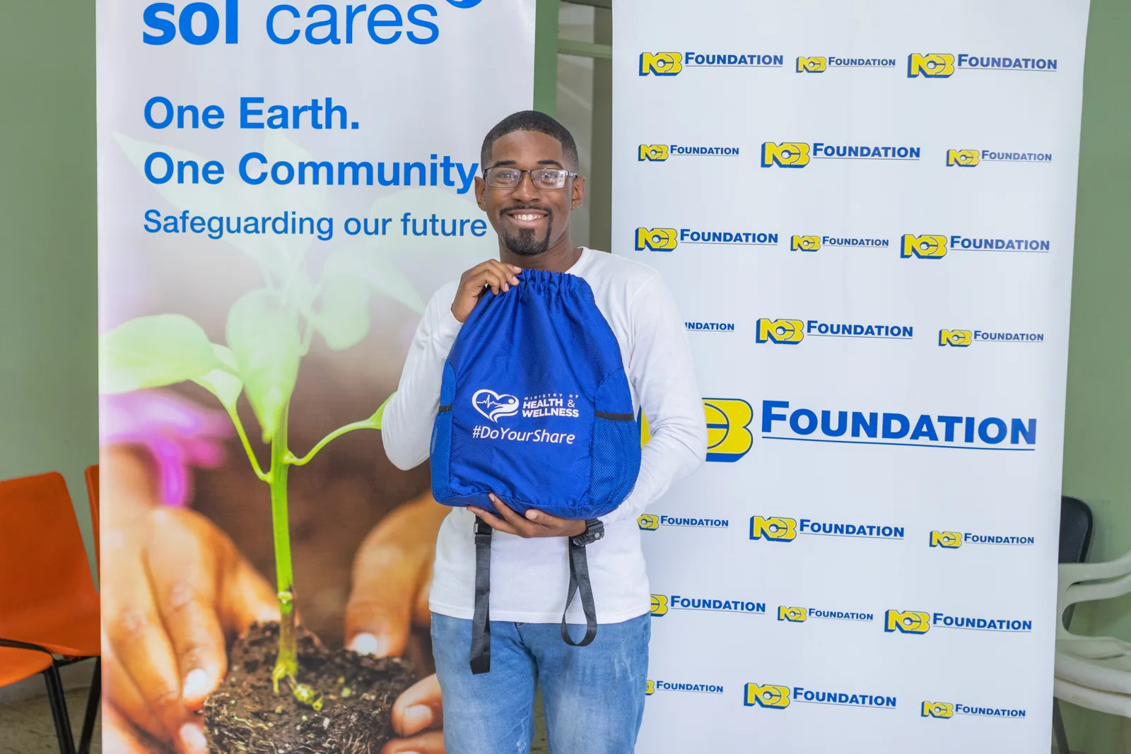 A participant holding a blue bag in front of the blood drive banners
