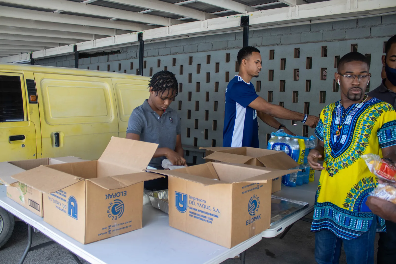 People preparing boxes of supplies beside a vehicle